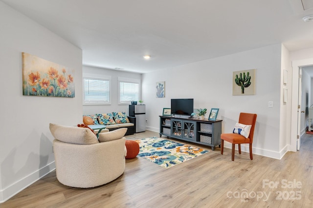 living area with baseboards and wood finished floors
