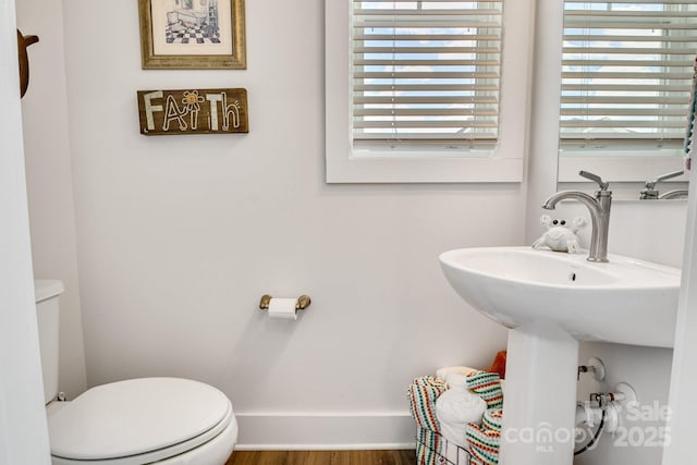 half bath with a healthy amount of sunlight, toilet, and wood finished floors