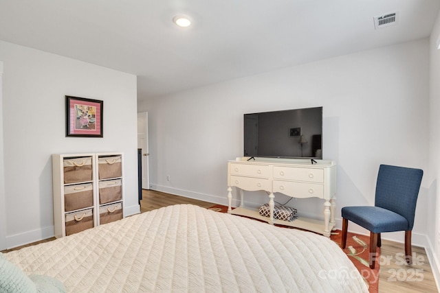 bedroom featuring baseboards, visible vents, and wood finished floors