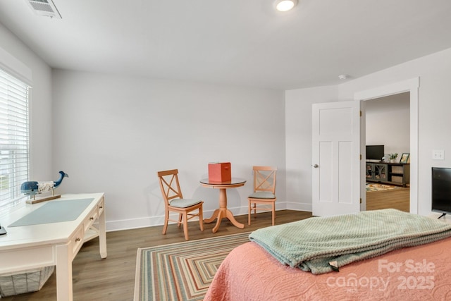 bedroom with baseboards, multiple windows, wood finished floors, and visible vents