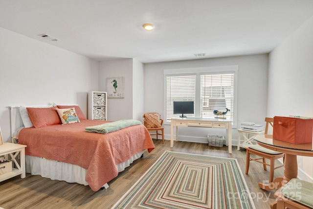 bedroom featuring visible vents, baseboards, and wood finished floors