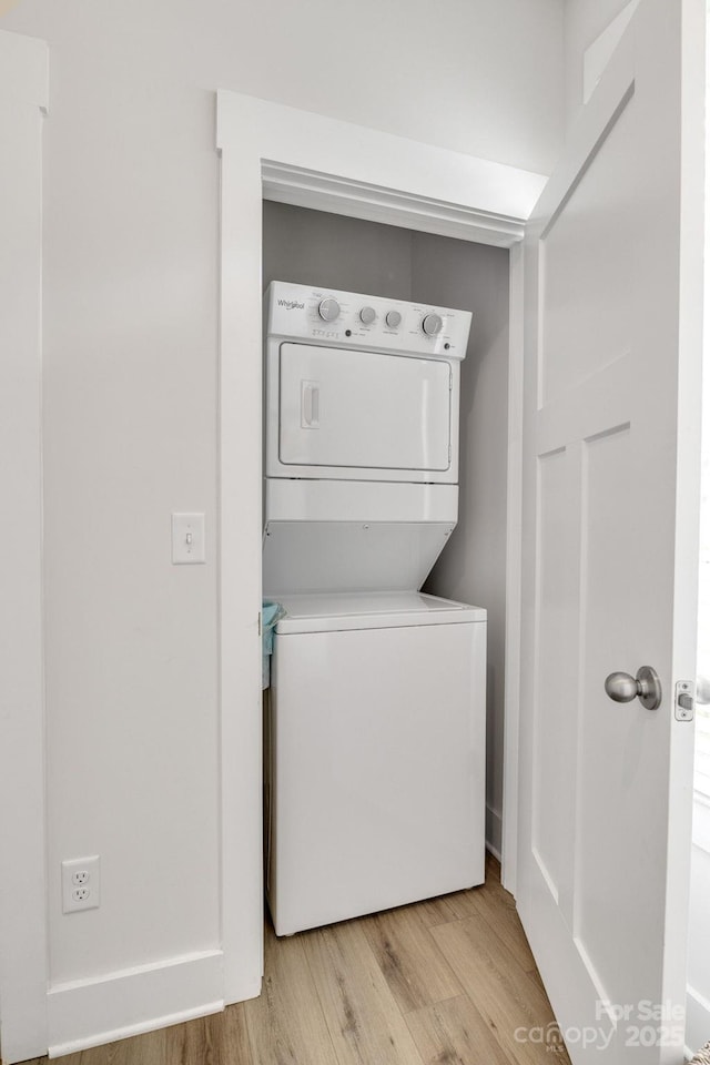 clothes washing area with laundry area, light wood finished floors, and stacked washer and clothes dryer