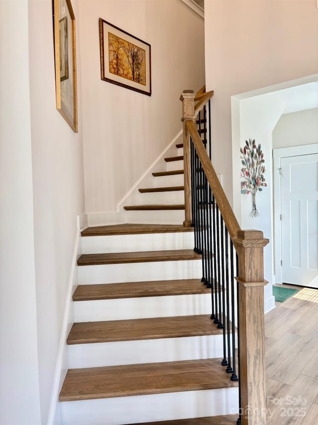 staircase featuring baseboards and wood finished floors