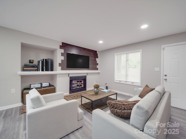 living area featuring baseboards, recessed lighting, wood finished floors, and a fireplace