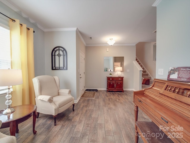 living area featuring wood-type flooring, baseboards, ornamental molding, and stairway