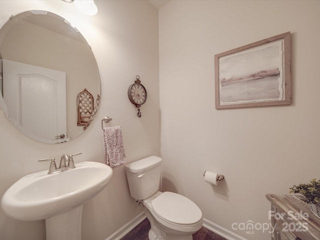 half bathroom featuring baseboards, a sink, and toilet