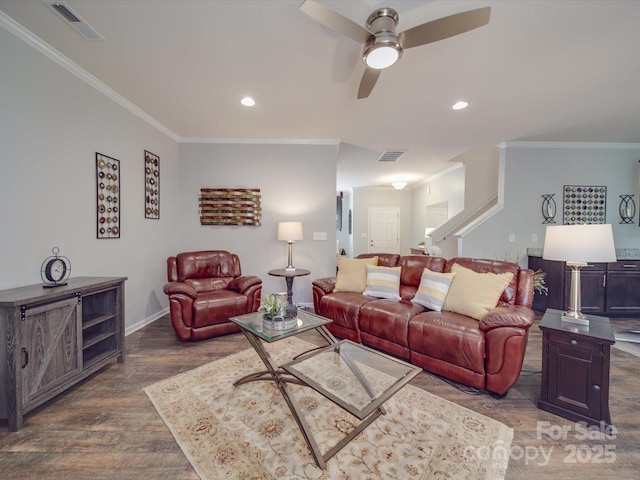 living area featuring ceiling fan, wood finished floors, visible vents, ornamental molding, and stairway