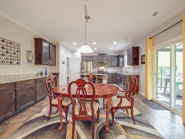 dining space with crown molding, recessed lighting, and wood finished floors