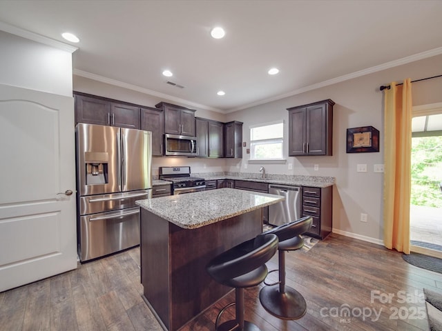 kitchen with appliances with stainless steel finishes, a center island, dark wood-style floors, and dark brown cabinetry