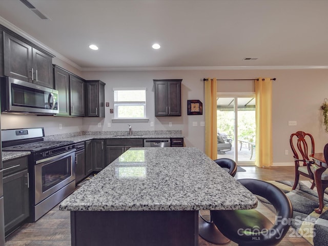kitchen with light stone countertops, a breakfast bar, a sink, a center island, and stainless steel appliances