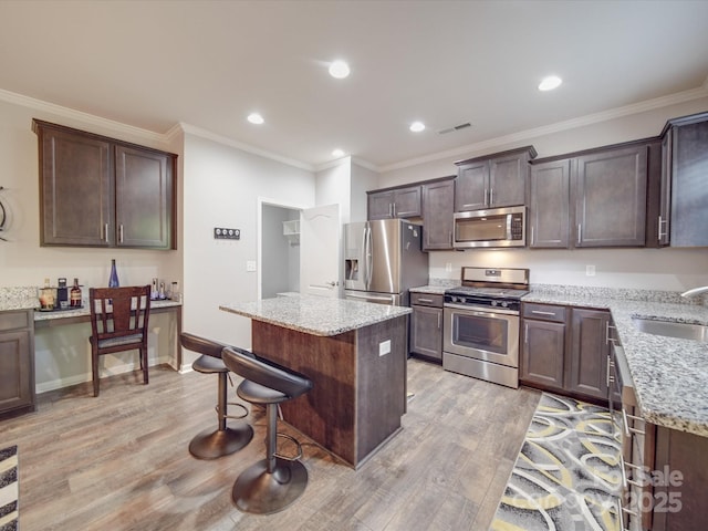 kitchen with visible vents, a center island, a sink, light wood finished floors, and stainless steel appliances