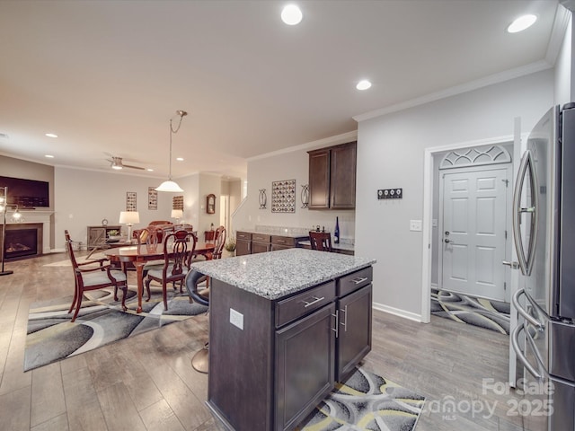 kitchen featuring dark brown cabinets, a fireplace, light wood-style floors, freestanding refrigerator, and open floor plan