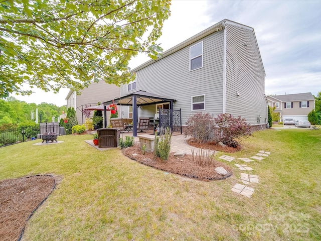 rear view of house featuring a yard, a gazebo, fence, and a fire pit