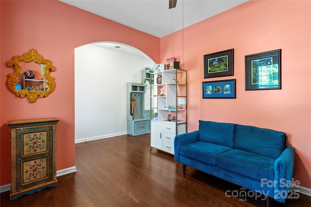 sitting room featuring dark wood-style flooring, baseboards, a ceiling fan, and arched walkways
