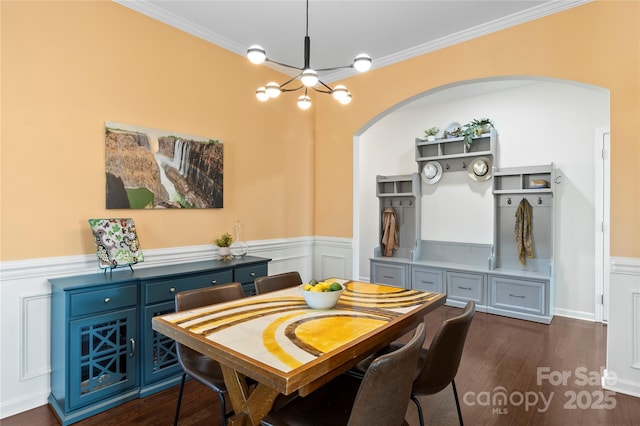 dining space with an inviting chandelier, arched walkways, dark wood finished floors, and crown molding
