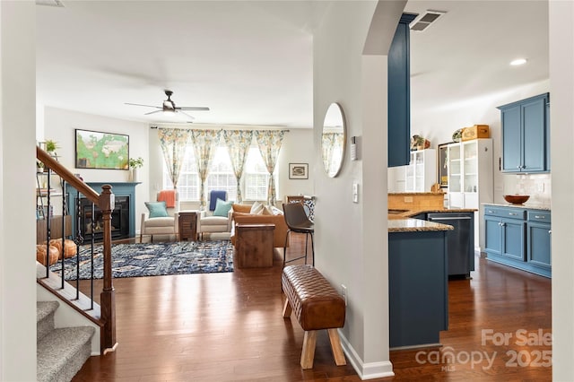 interior space featuring arched walkways, dark wood finished floors, ceiling fan, and stairs