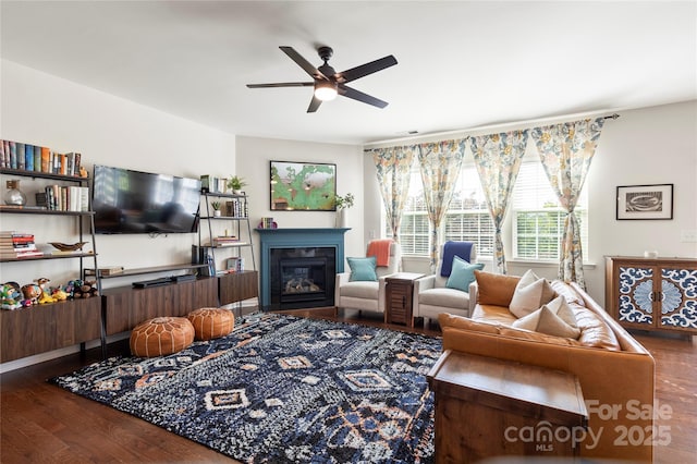 living room featuring a ceiling fan, a glass covered fireplace, and wood finished floors