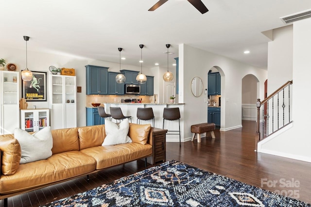 living area with a ceiling fan, visible vents, arched walkways, dark wood finished floors, and recessed lighting