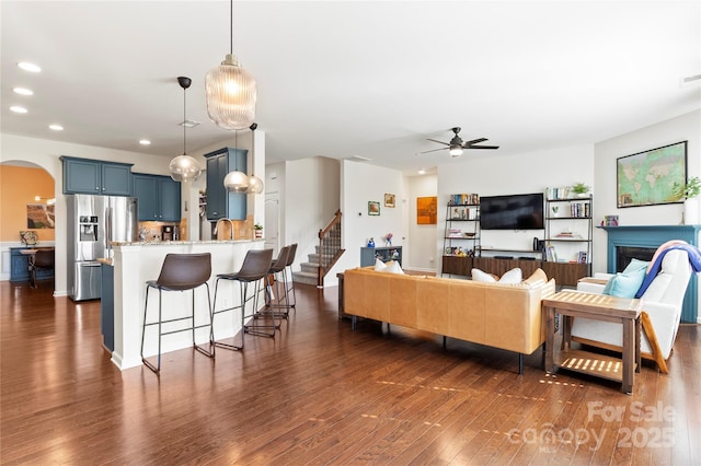 living room featuring a ceiling fan, stairs, dark wood-style floors, recessed lighting, and arched walkways