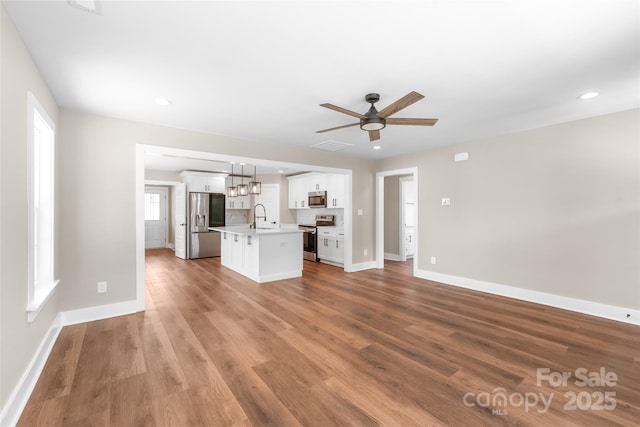 640 Central Dr NW, Concord, NC 28027 - unfurnished living room featuring baseboards, a sink, light wood-style flooring, and a ceiling fan