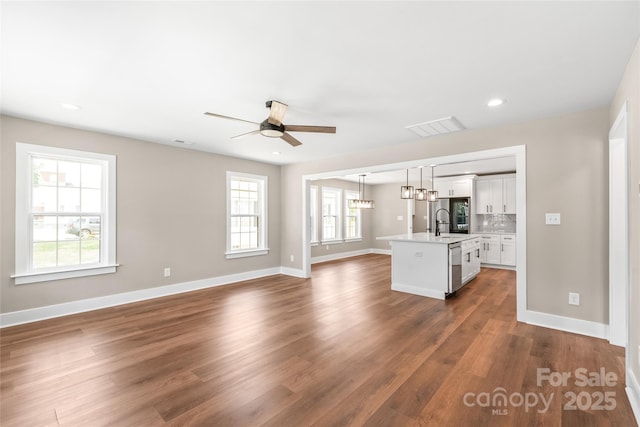 640 Central Dr NW, Concord, NC 28027 - unfurnished living room featuring ceiling fan, dark wood-style flooring, visible vents, a sink, and baseboards