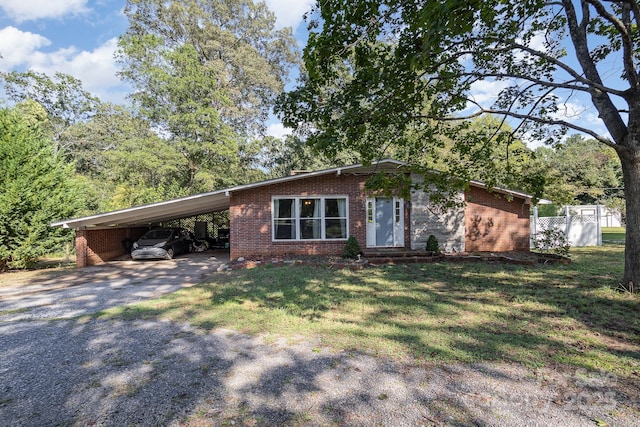 single story home featuring a carport, gravel driveway, a front lawn, and brick siding