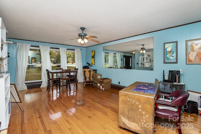 living room with a ceiling fan, a textured ceiling, and light wood-style flooring