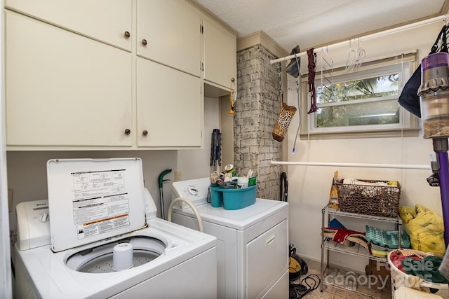 clothes washing area with cabinet space, washing machine and dryer, and a textured ceiling