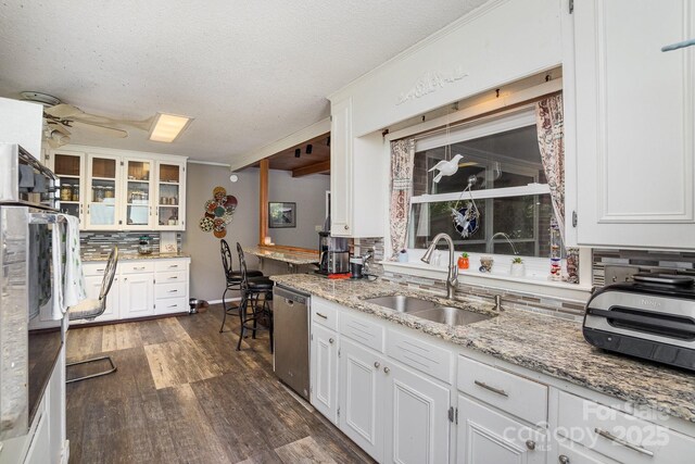 kitchen featuring stainless steel dishwasher, dark wood-style floors, a sink, a textured ceiling, and decorative backsplash