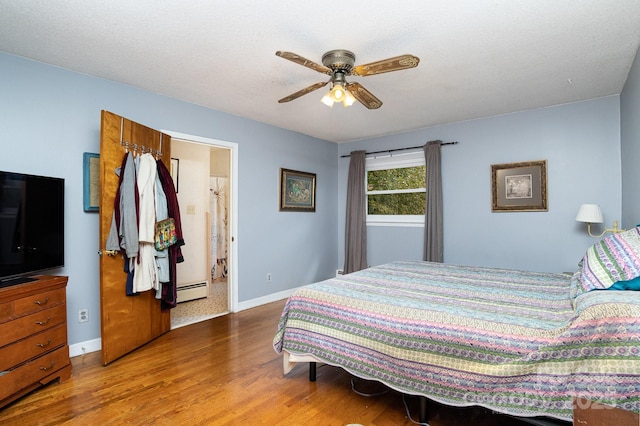 bedroom with baseboards, wood finished floors, a ceiling fan, and baseboard heating