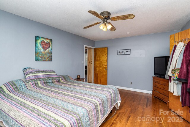 bedroom featuring baseboards, a ceiling fan, wood finished floors, and a textured ceiling