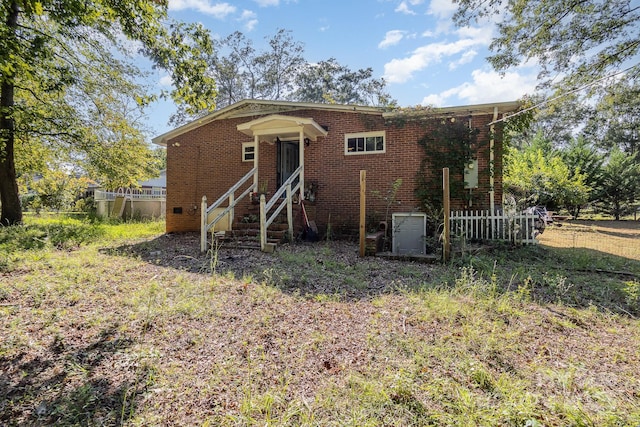 view of front of house featuring brick siding and fence