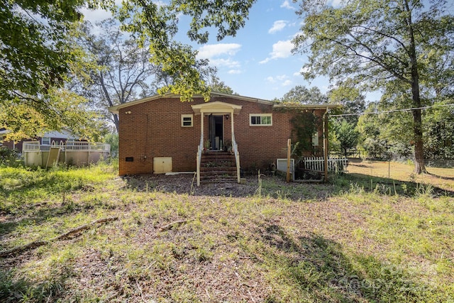 rear view of property with fence, entry steps, and brick siding