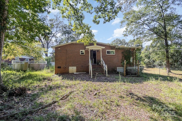 back of house featuring fence, crawl space, entry steps, and brick siding