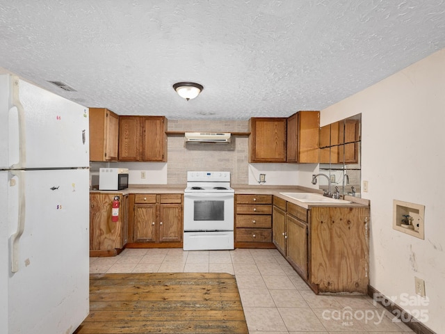 kitchen featuring white appliances, brown cabinets, ventilation hood, and a sink