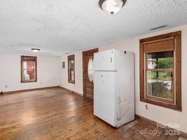 kitchen featuring a textured ceiling, freestanding refrigerator, baseboards, visible vents, and hardwood / wood-style flooring