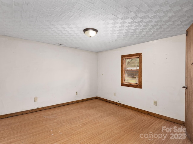 spare room with baseboards and light wood finished floors