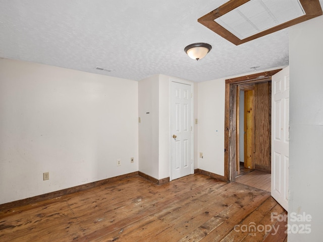 spare room with baseboards, hardwood / wood-style flooring, a textured ceiling, and visible vents