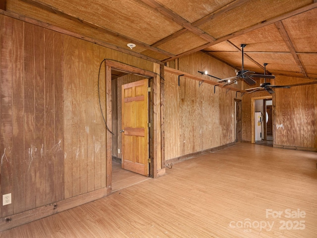 unfurnished room featuring wooden walls, ceiling fan, and wood finished floors