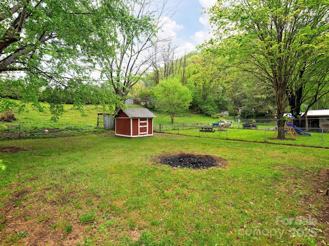 view of yard with a storage shed, fence, an outbuilding, and a playground