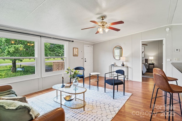 living area with crown molding, a textured ceiling, ceiling fan, and wood finished floors