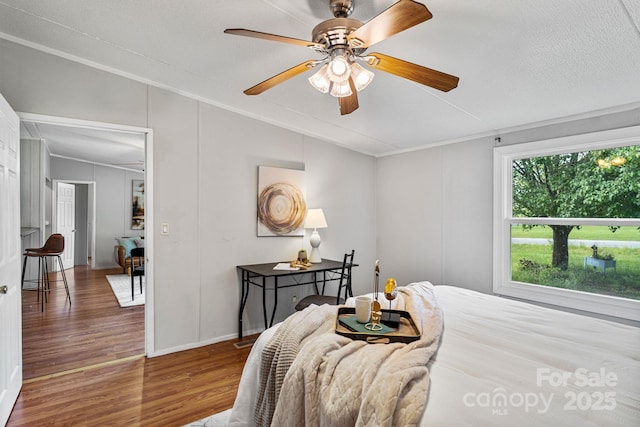 bedroom featuring ceiling fan, crown molding, wood finished floors, baseboards, and lofted ceiling