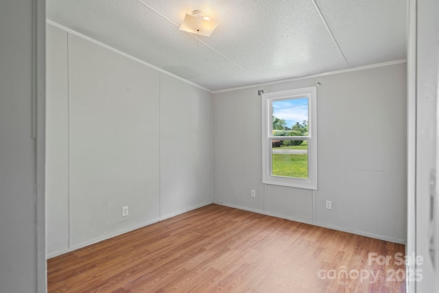 spare room with baseboards, a textured ceiling, ornamental molding, and wood finished floors