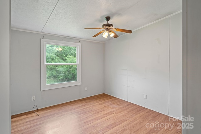 empty room featuring a ceiling fan, light wood finished floors, and ornamental molding