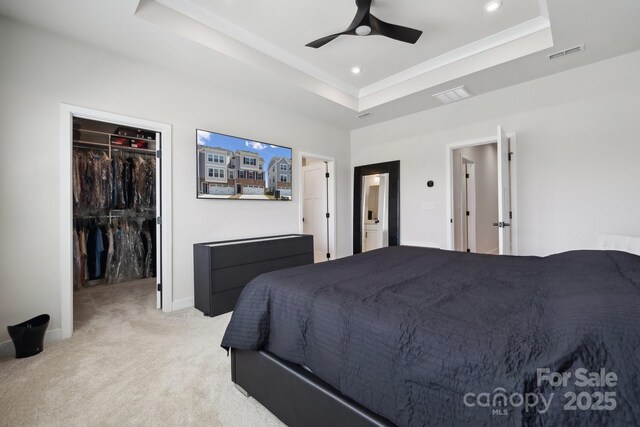 bedroom featuring a raised ceiling, a spacious closet, visible vents, and light carpet