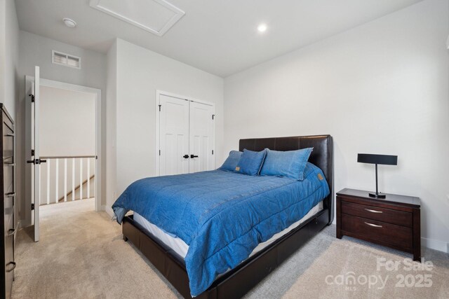 bedroom featuring attic access, a closet, visible vents, baseboards, and light colored carpet