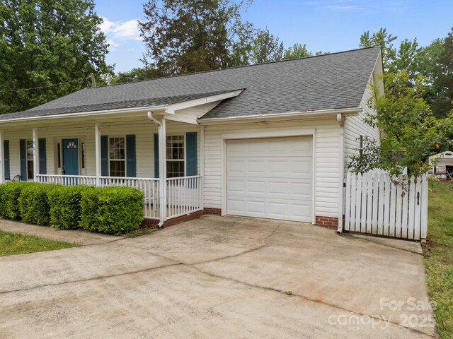 ranch-style home with covered porch, a garage, a shingled roof, and concrete driveway