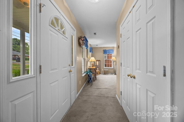 corridor with a wealth of natural light, visible vents, carpet flooring, and baseboards