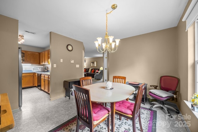 dining space featuring an inviting chandelier, visible vents, and baseboards