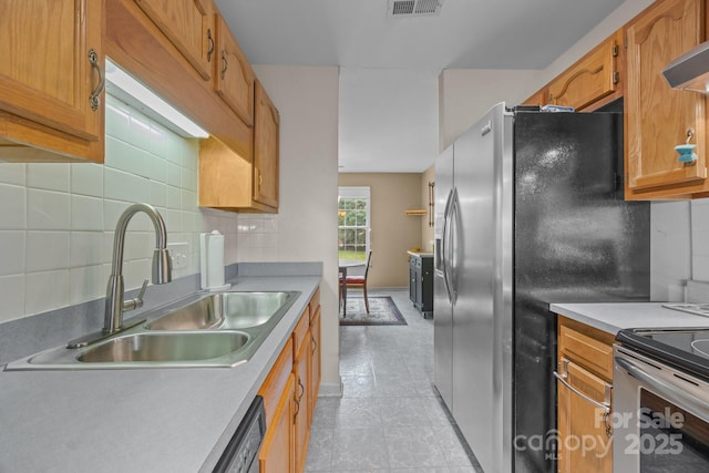 kitchen featuring wall chimney exhaust hood, a sink, stainless steel appliances, and light countertops